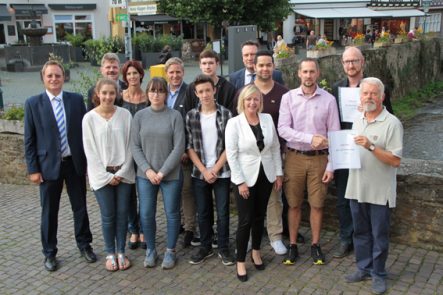 Bodo Kerstin (rechts) überreichte die Urkunden für den ersten und zweiten Preis an Nikolaus Weiler und Ingo Pfennings vom Stadtmarketingverein. Die Schülerinnen und Schüler sowie Schulleiter Bernhard Helfer (links) freuten sich, ihr Projekt doch noch umgesetzt zu haben. Bürgermeisterin Sabine Preiser-Marian (vorne) und die Sponsoren der KSK (Hintergrund) konnte sich über das Engagement in der Kurstadt nicht beklagen. Bild: Michael Thalken/Eifeler Presse Agentur/epa